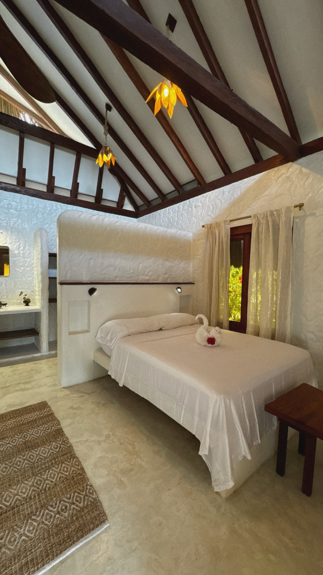 Bright bedroom with vaulted wooden ceiling and white linens